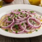 A fresh cebolla ensalada with red onions and parsley on a white plate