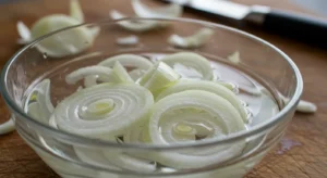 Thinly sliced onions soaking in water for cebolla ensalada preparation