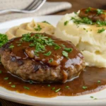 A delicious Salisbury steak made with ground chicken, topped with savory brown gravy and served alongside creamy mashed potatoes. Perfect for a healthy family dinner!