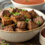 Juicy and tender air fryer steak bites served with fresh herbs and a dipping sauce, perfect for any meal or appetizer.