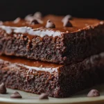 Close-up of fudgy, moist zucchini brownies with a gooey chocolate texture and a rich chocolatey top.