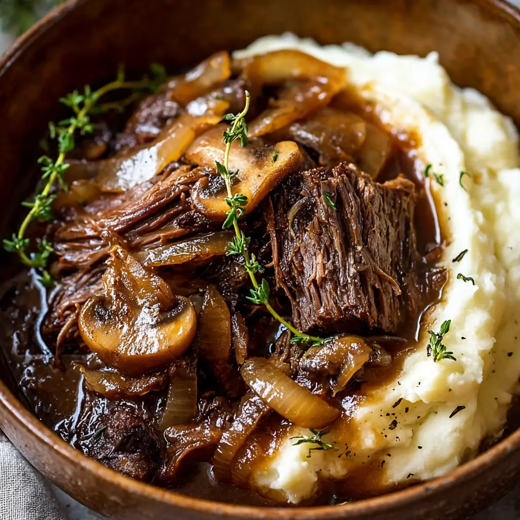 Slow Cooker French Onion Mushroom Pot Roast served with caramelized onions, mushrooms, and mashed potatoes